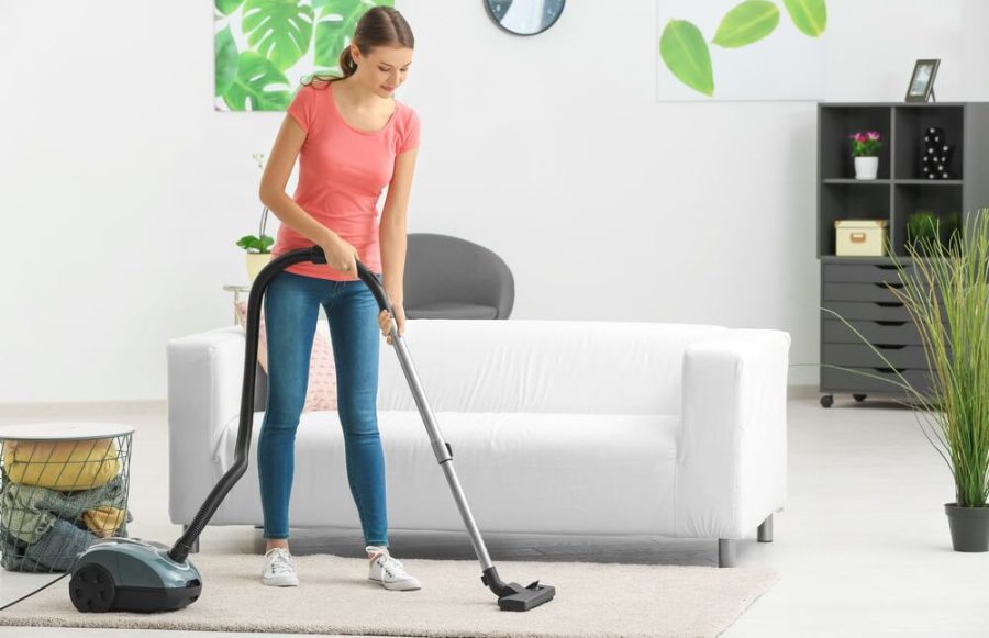 Young woman using Vacuum Cleaner e1638211264170
